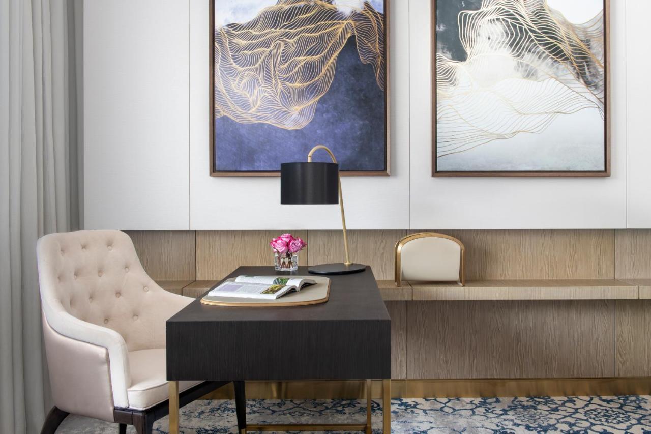 Steigenberger Hotel Doha Exterior foto The photo depicts a stylish office or study area. In the foreground, there is a dark wooden desk with a few items on it, including a notepad and a small vase of flowers. A modern black lamp is placed on the desk, providing a sophisticated touch. 

Ad