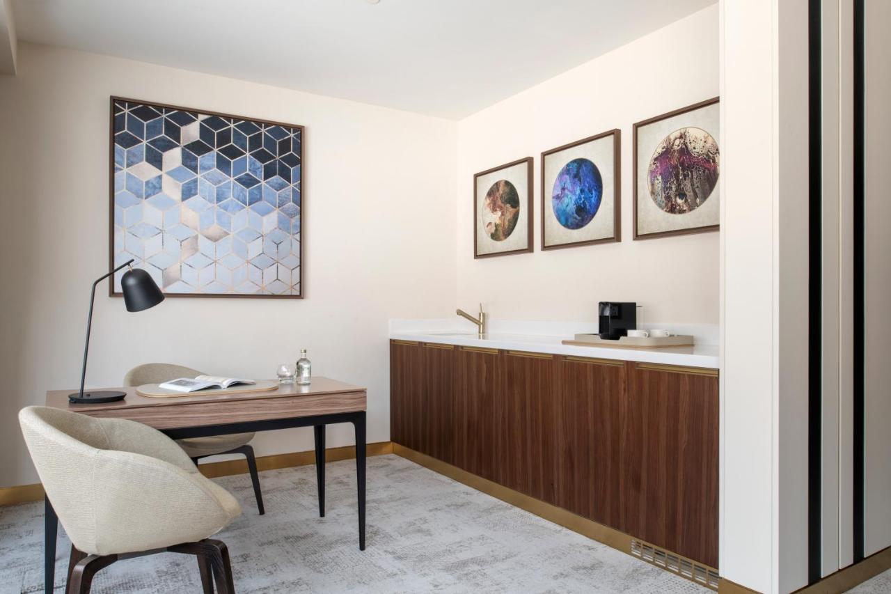 Steigenberger Hotel Doha Exterior foto The photo shows a modern, stylish office or study area. There's a wooden desk with a minimalist design and a comfortable chair. On the desk, there is an open book and a small decorative item. A sleek desk lamp is positioned on one end of the desk. 

