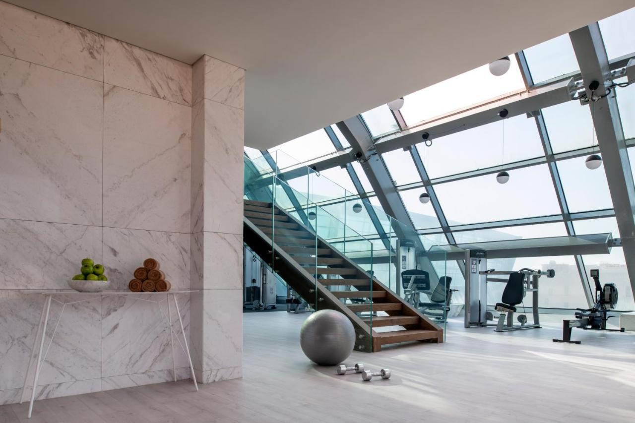 Steigenberger Hotel Doha Exterior foto The photo showcases a modern, stylish interior space, likely a gym or fitness area. Key features include:

- **Large Windows**: The room is filled with natural light due to its expansive glass walls and ceiling.
- **Staircase**: A wooden staircase le