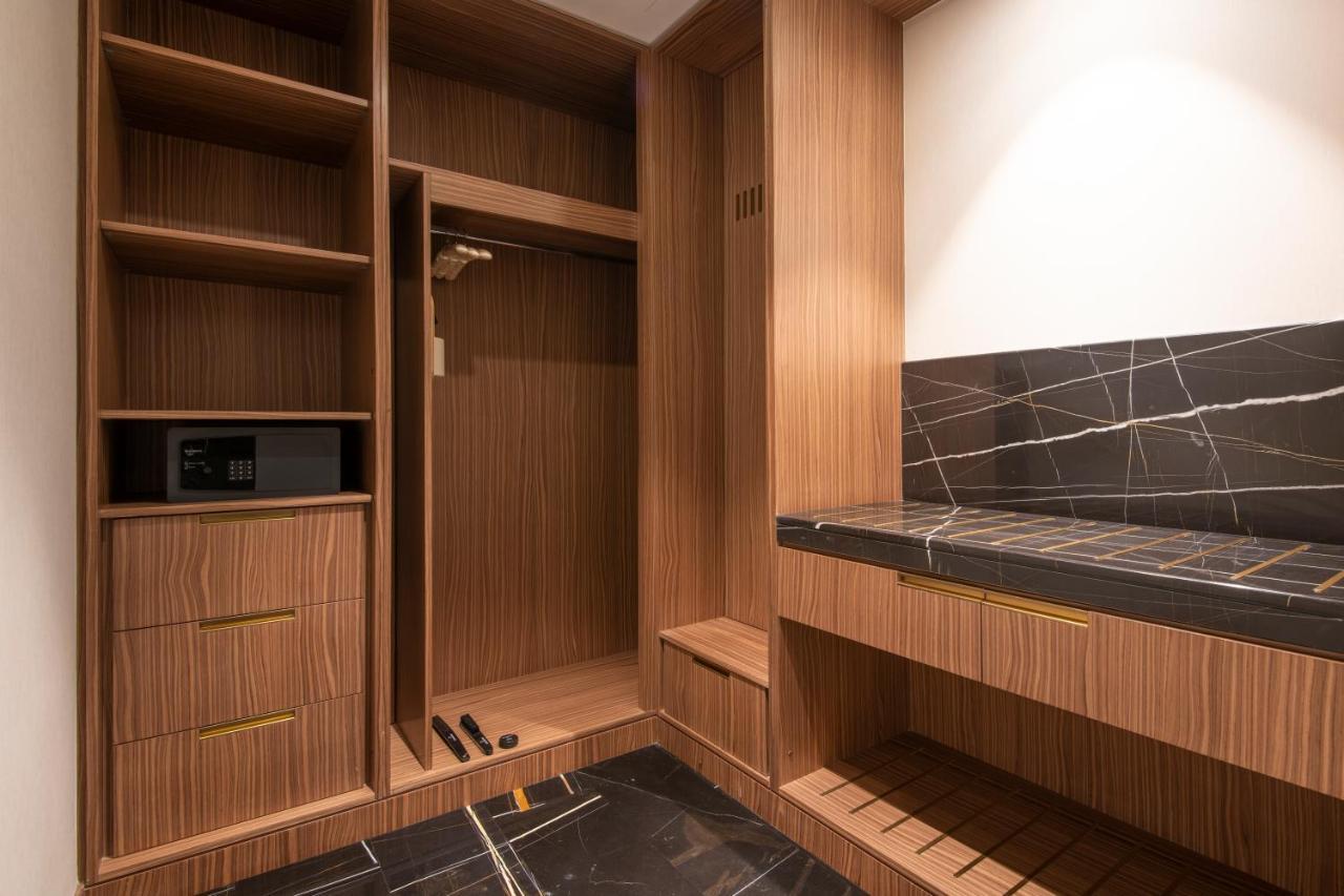Steigenberger Hotel Doha Exterior foto The photo shows a stylishly designed closet or wardrobe area. It features wooden panels with a warm finish. On the left side, there are open shelves, as well as a section for hanging clothes. Below, there are two drawers, adding extra storage space. 