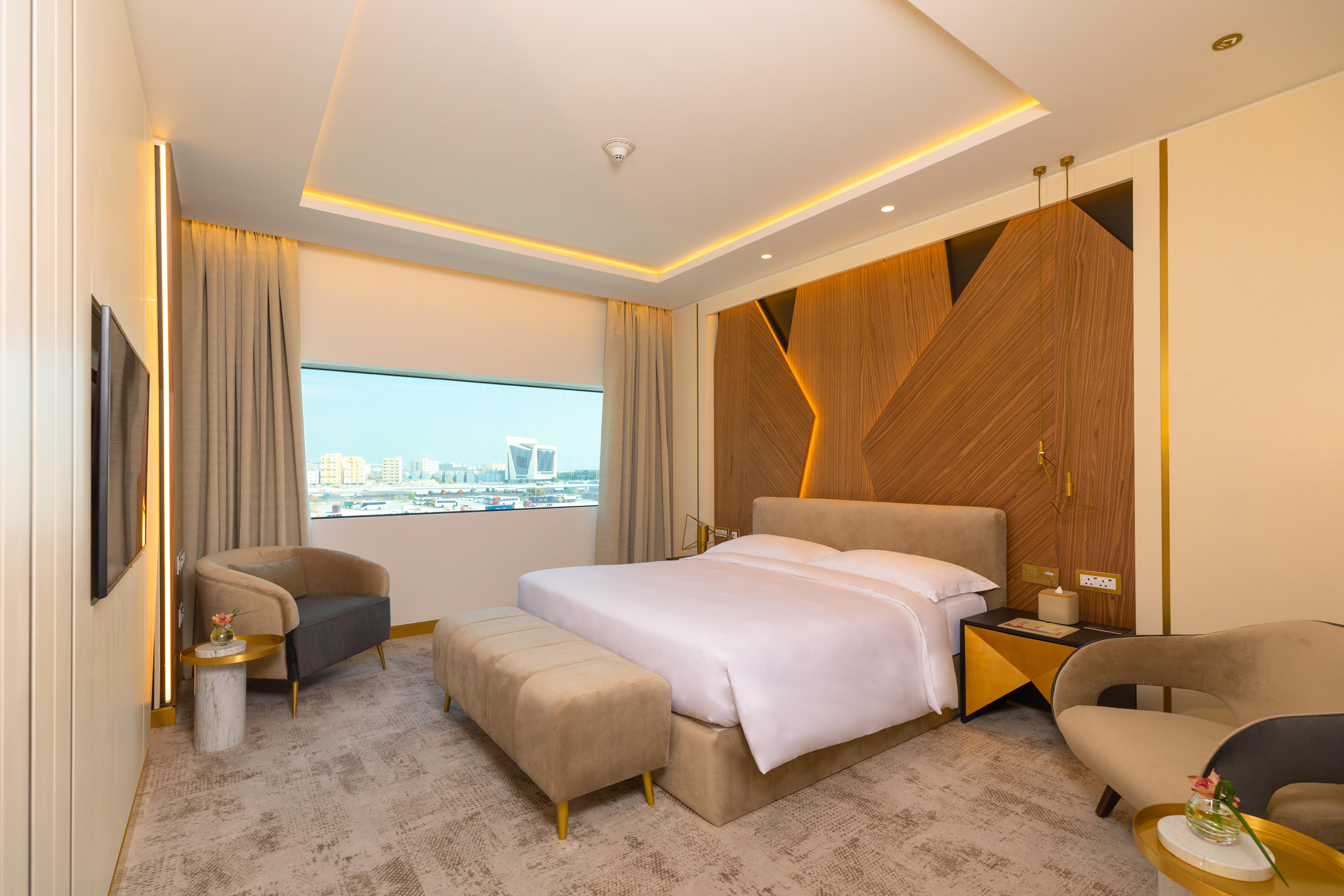 Steigenberger Hotel Doha Exterior foto The photo showcases a modern hotel room with a stylish and contemporary design. It features a spacious layout with a large bed placed in the center, dressed in white linens. Behind the bed is an accent wall made of wood, which adds warmth and texture