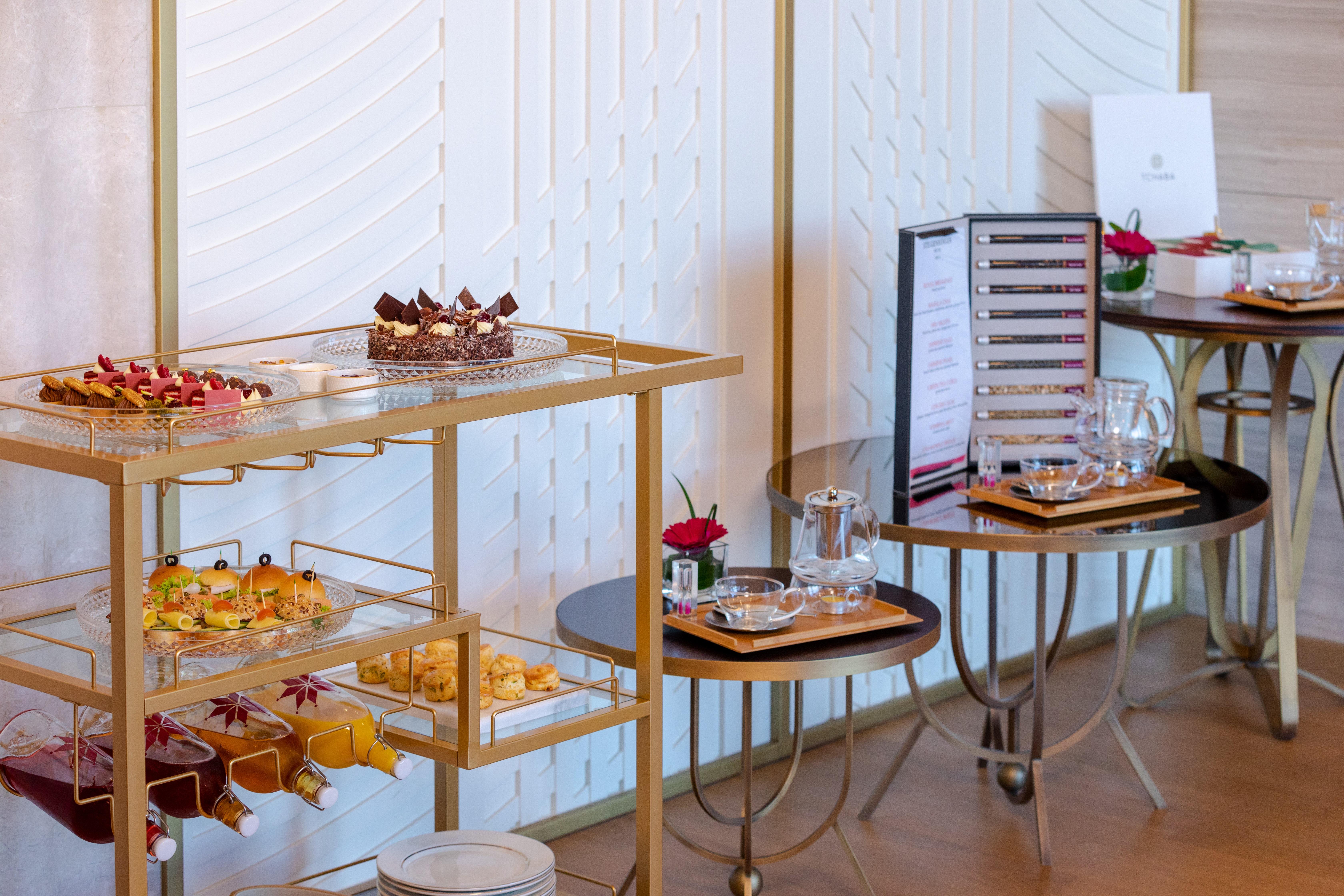 Steigenberger Hotel Doha Exterior foto The photo shows a beautifully arranged buffet table featuring a variety of desserts and snacks. There is a gold cart displaying an assortment of pastries and small treats, including colorful hors d'oeuvres and mini desserts, likely for a high-end eve
