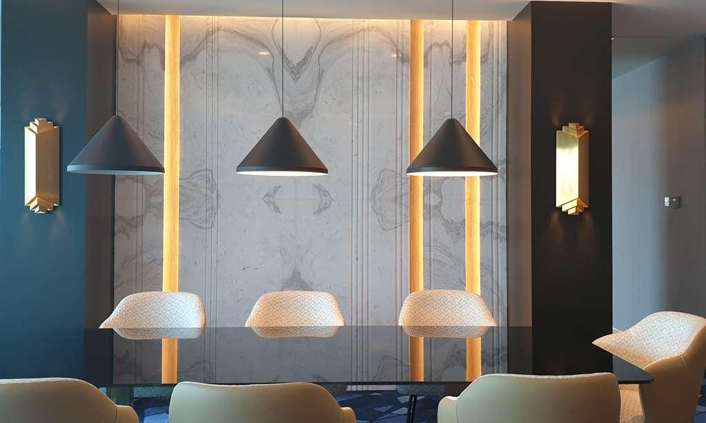Steigenberger Hotel Doha Habitación foto The photo showcases a modern interior space featuring a sleek design. The focal point is a wall adorned with a marble-like texture, enhanced by vertical lighting strips that add warmth to the environment. Above a table or counter are three pendant li